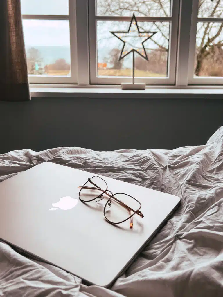 Laptop i okulary na pościeli, w oknie świecąca gwiazda, a za szybą morze