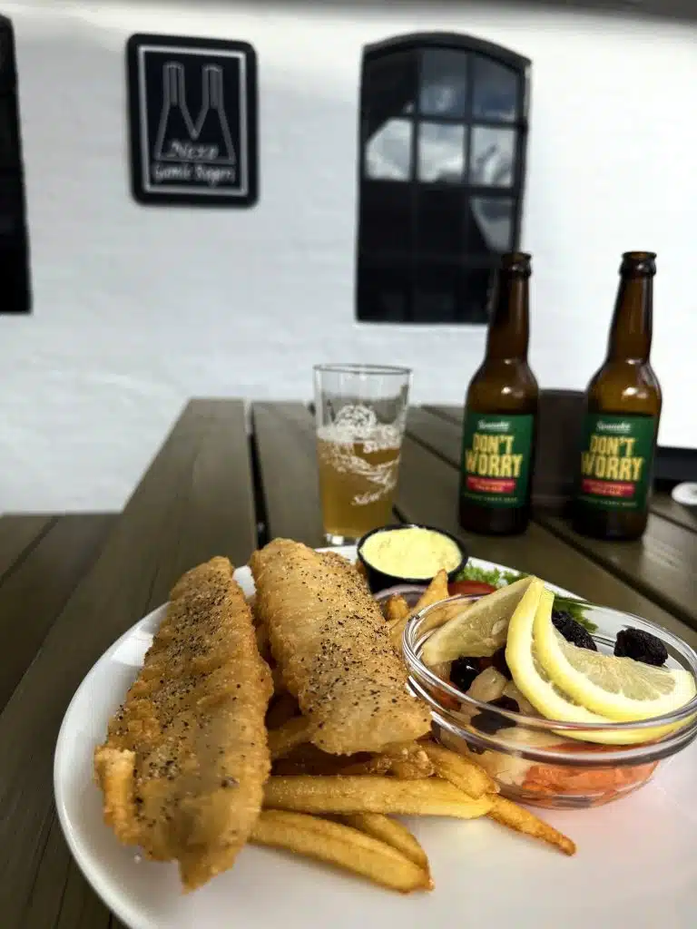Fish and chips, dwa piwa Don’t Worry ze Svaneke Bryghus i szklanka na stole pod szyldem Nexø Gamle Røgeri