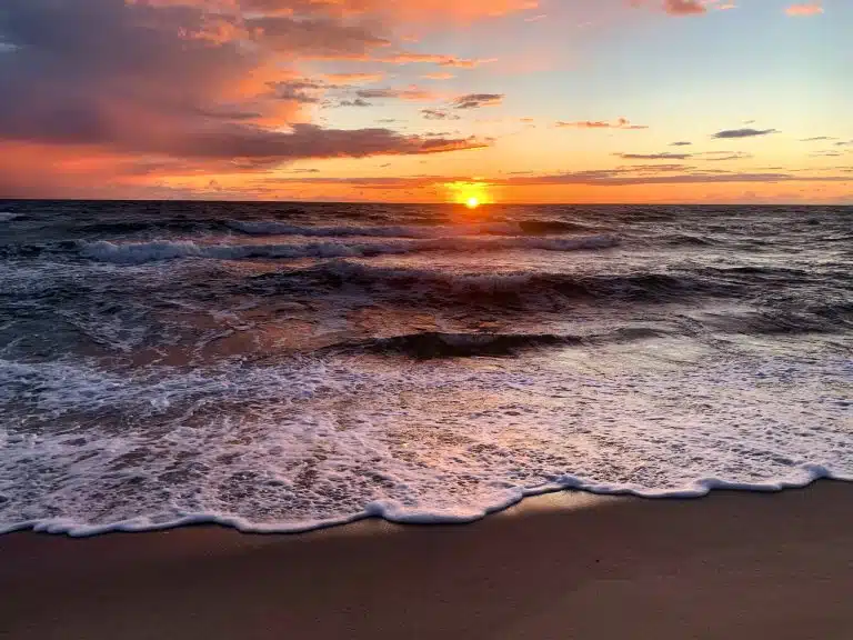 Zachodzące słońce nad Bałtykiem, spieniona fala na piaszczystej plaży
